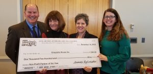 Four smiling people in business attire hold a large ceremonial check made out to Chrysalis House Inc. for $1,500 from the Anne Arundel Affordable Housing Coalition, dated December 14, 2018, for Non-Profit Partner of the Year.