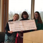 Three women smiling and holding a large ceremonial check from The Anne Arundel Association of REALTORS® for $1,500, dated December 14, 2018, awarded to The Light House. Trees and windows are visible in the background.