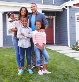 family smiling in front of house